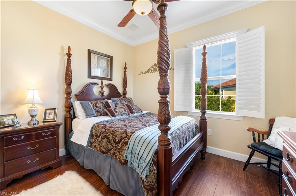 Bedroom with dark wood-style floors, ornamental molding, and a ceiling fan