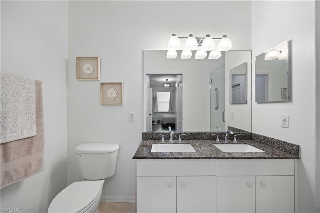 Bathroom with tile patterned flooring, vanity, a shower with door, and toilet