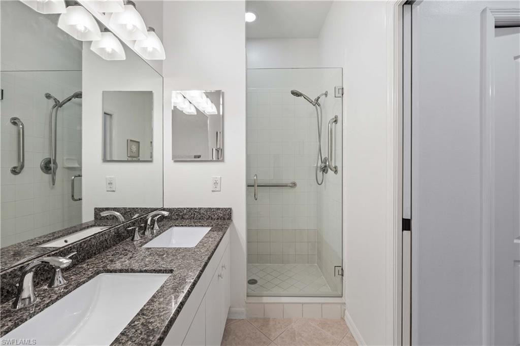 Bathroom featuring tile patterned floors, vanity, and walk in shower