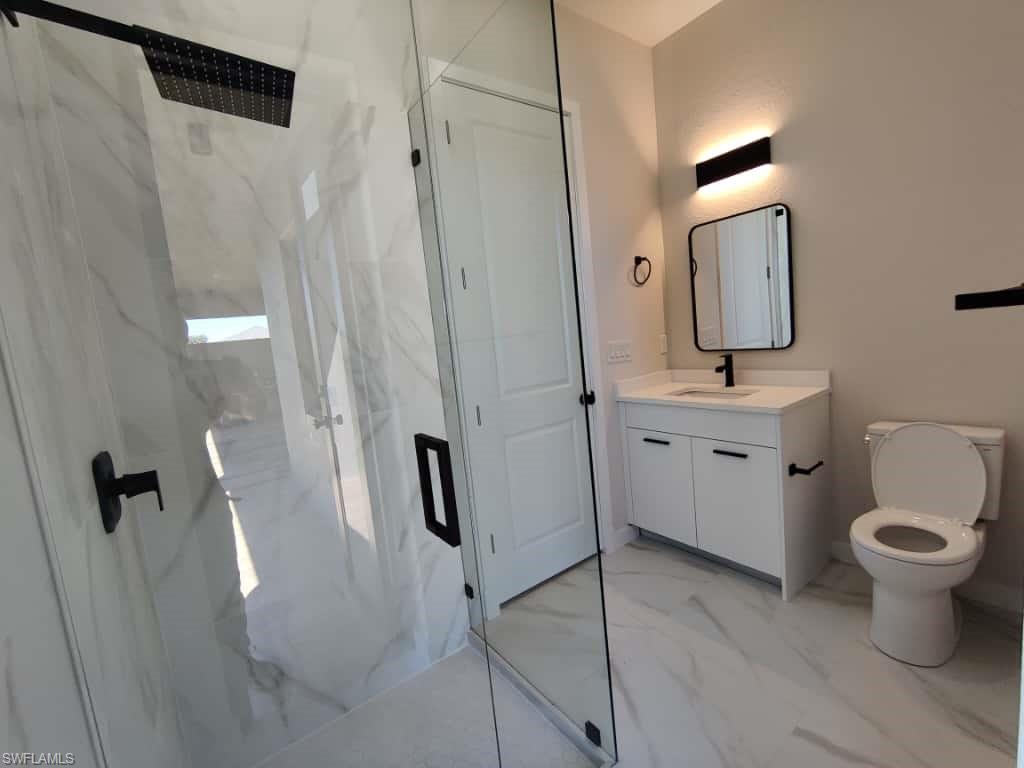 Full bathroom featuring a marble finish shower, vanity, and light marble finish flooring