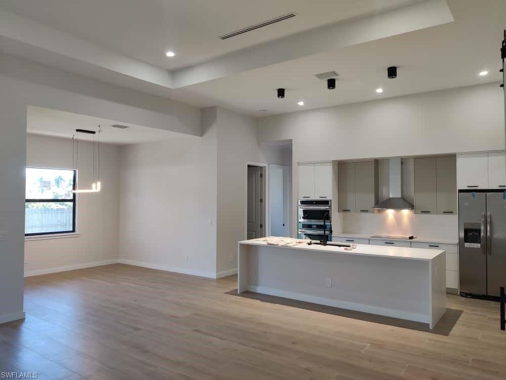 Kitchen with stainless steel appliances, light wood-type flooring, a center island with sink, and modern cabinets