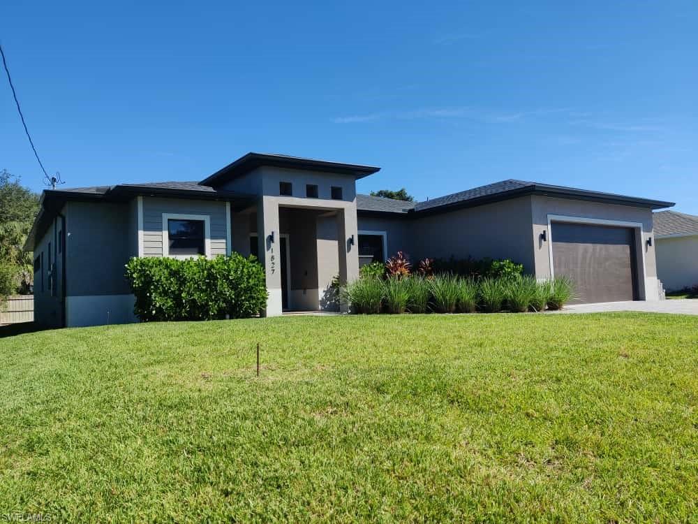 Prairie-style house featuring an attached garage, a front lawn, stucco siding, and driveway