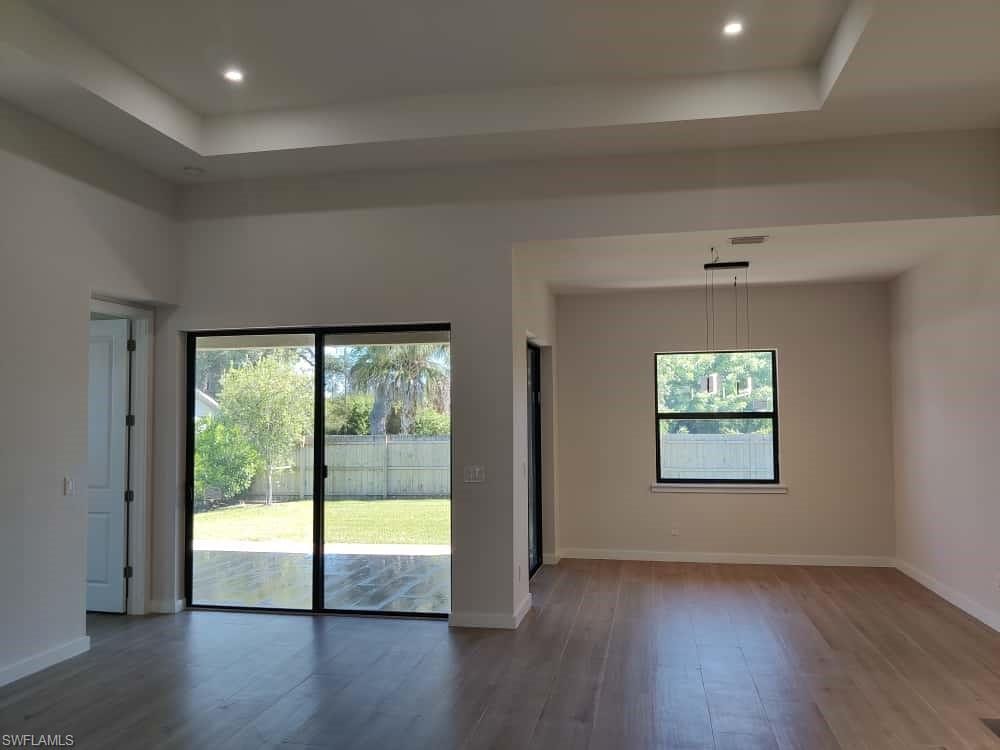 Unfurnished living room featuring a tray ceiling, dark wood-style flooring, and recessed lighting