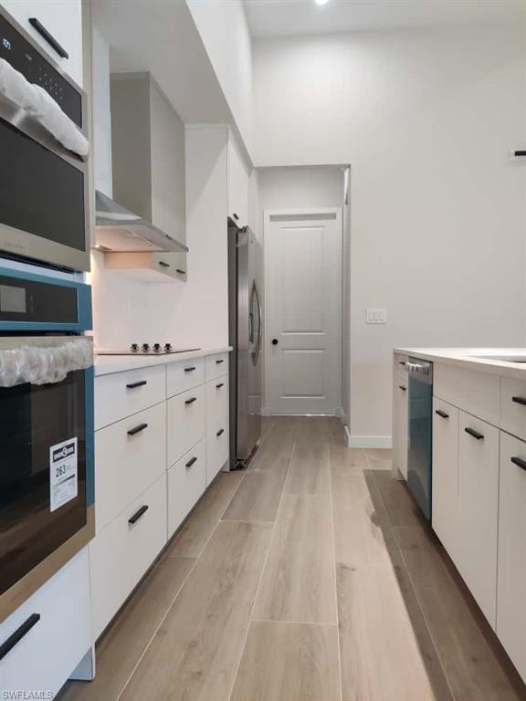 Kitchen with white cabinets, modern cabinets, light countertops, and light wood-type flooring