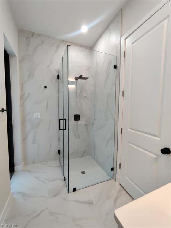 Full bath with marble tiled floors, a marble finish shower, recessed lighting, and vanity