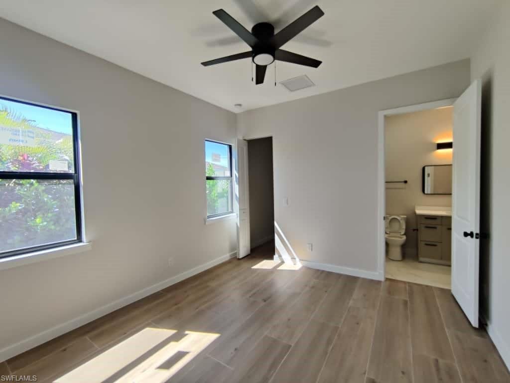 Unfurnished bedroom featuring light wood-type flooring, a ceiling fan, and connected bathroom