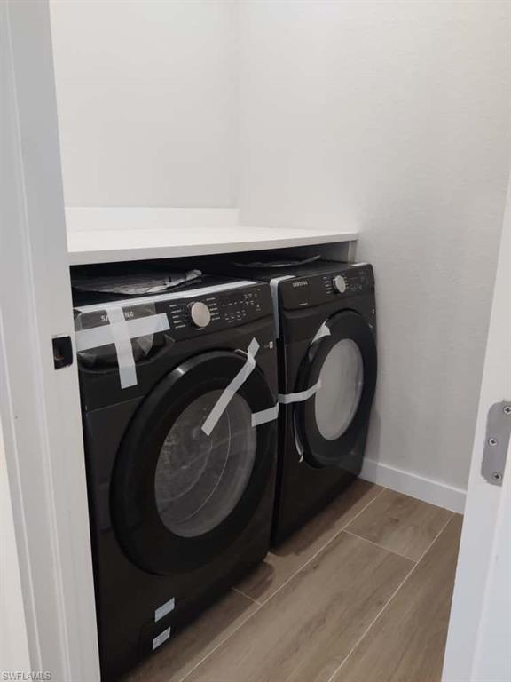 Laundry room featuring washing machine and dryer and wood finish floors