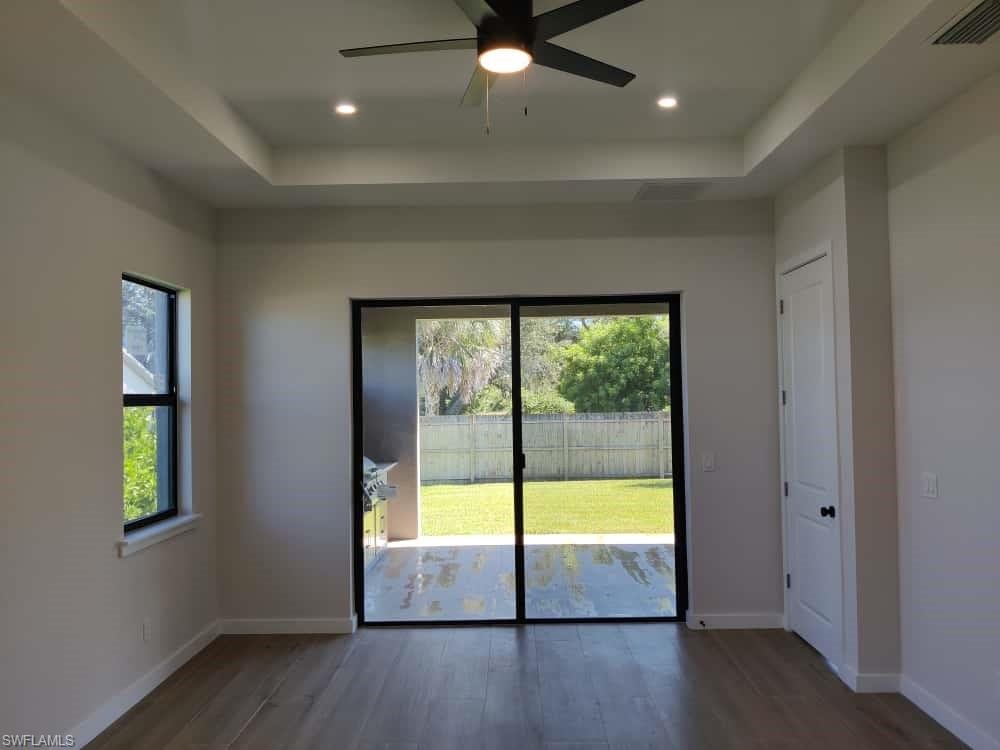 Unfurnished room featuring a raised ceiling, dark wood-style flooring, a ceiling fan, and recessed lighting