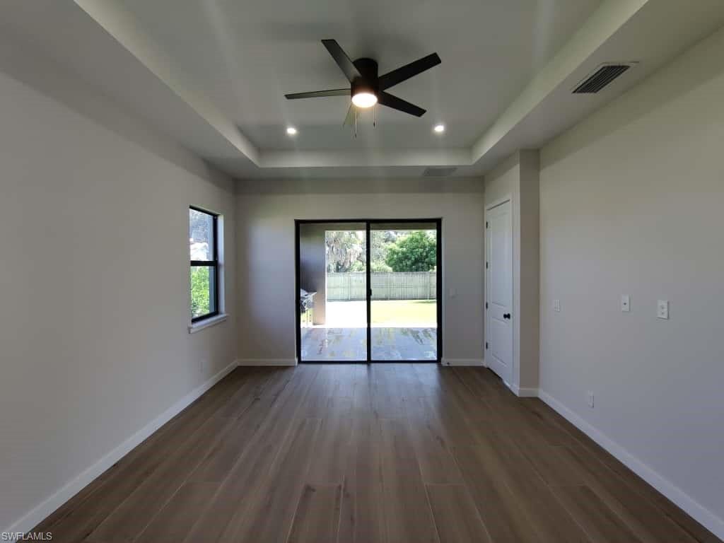 Spare room with dark wood finished floors, a tray ceiling, recessed lighting, and a ceiling fan