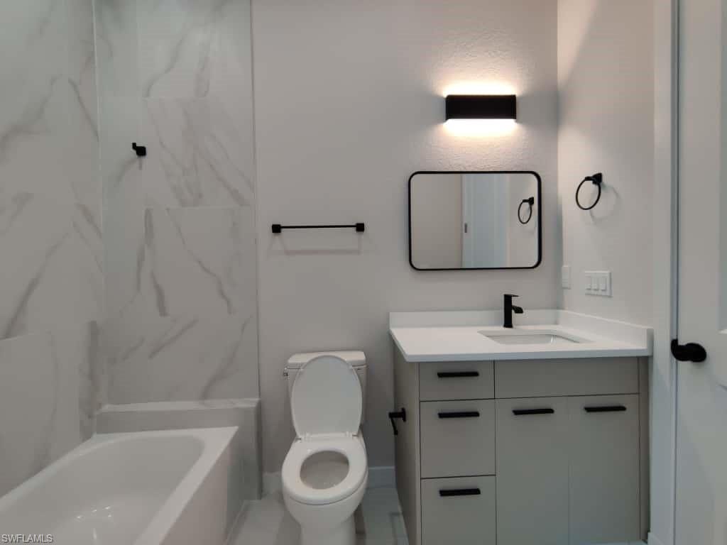 Full bathroom with vanity and a combined bath / shower with marble appearance
