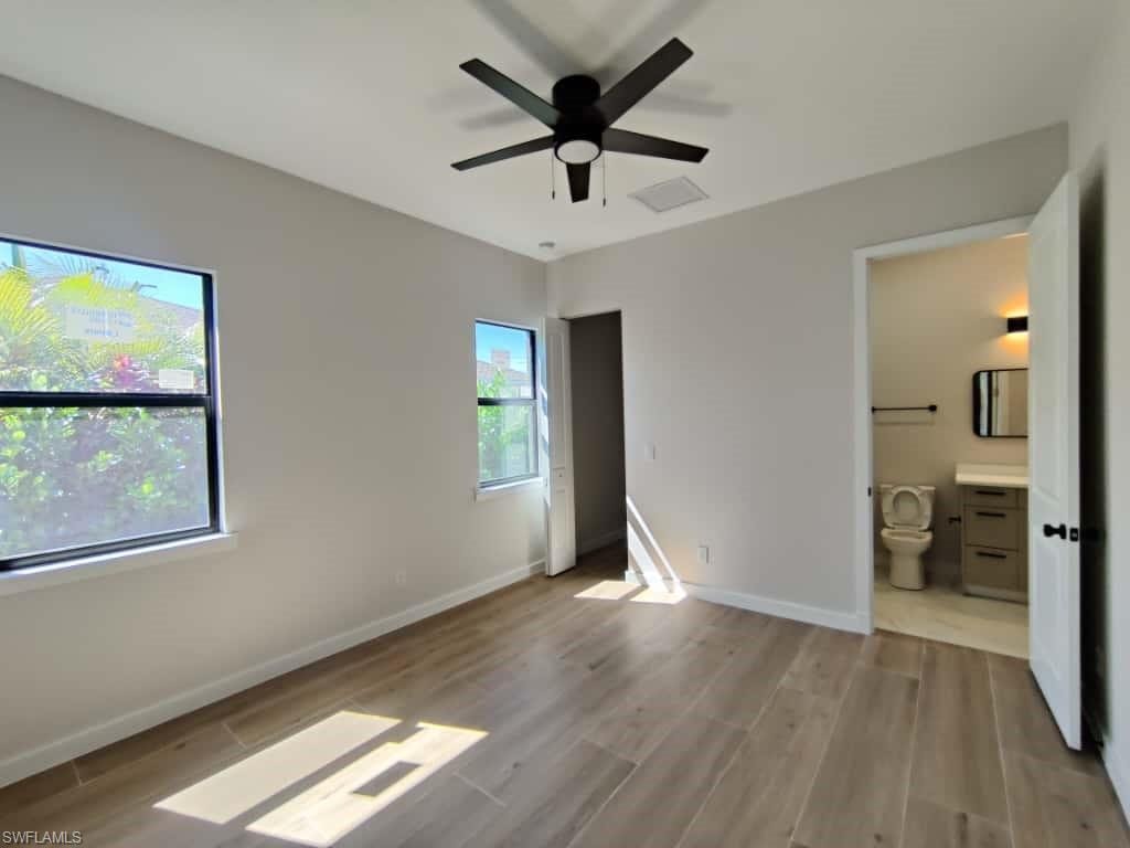 Unfurnished bedroom featuring light wood-type flooring, ceiling fan, and ensuite bathroom