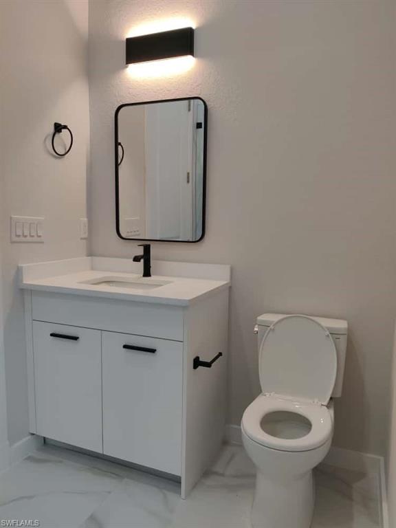 Half bathroom with light marble finish floors and vanity