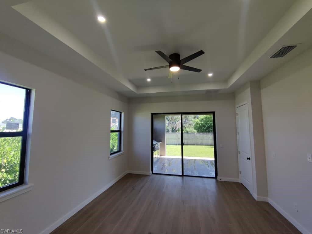 Spare room featuring a tray ceiling, dark wood-style floors, ceiling fan, and recessed lighting