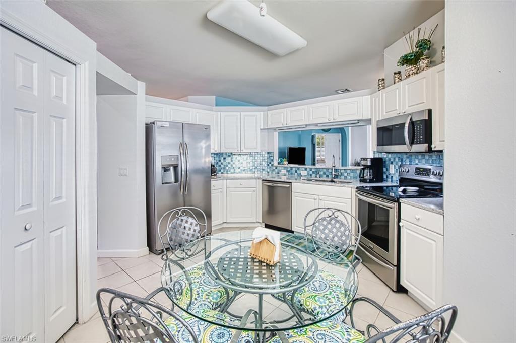Kitchen featuring appliances with stainless steel finishes, white cabinetry, decorative backsplash, and light tile patterned floors