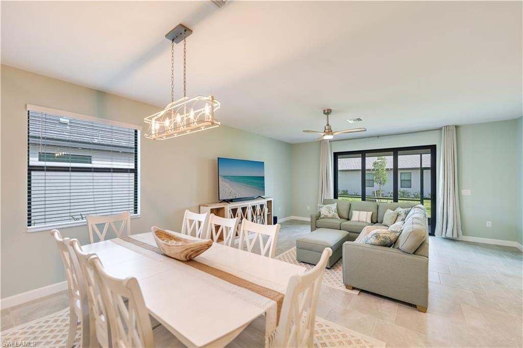 Tiled dining room featuring ceiling fan with notable chandelier