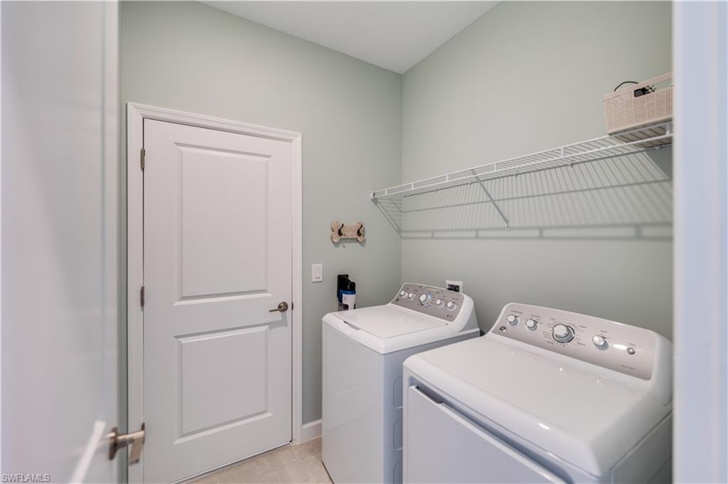 Washroom featuring light tile patterned flooring and washer and dryer