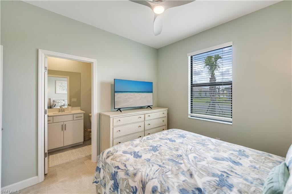 Bedroom featuring light tile patterned flooring, sink, ceiling fan, and connected bathroom
