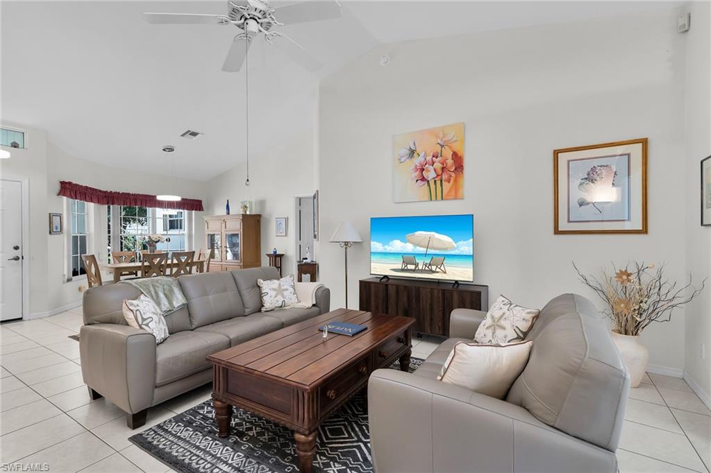 Living room featuring light tile patterned flooring, high vaulted ceiling, and a ceiling fan