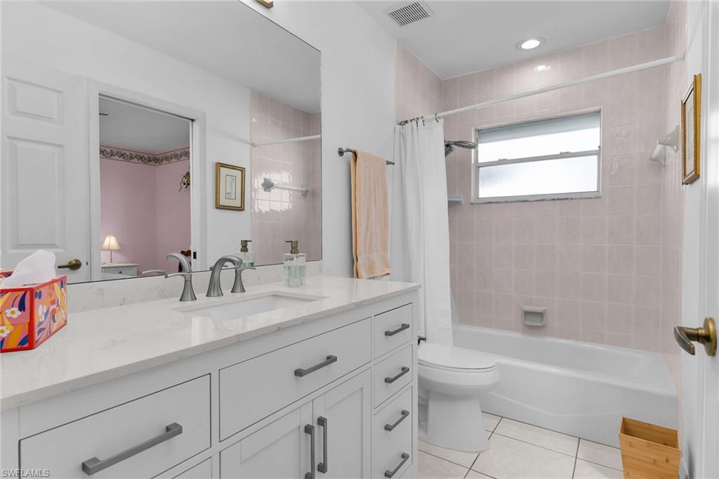 Full bath with vanity, light tile patterned floors, and shower / bathtub combination with curtain