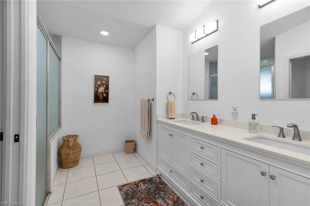 Full bath featuring light tile patterned flooring, double vanity, a shower with door, and recessed lighting