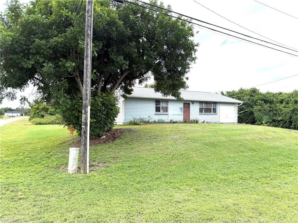 Ranch-style home featuring a front lawn and a garage