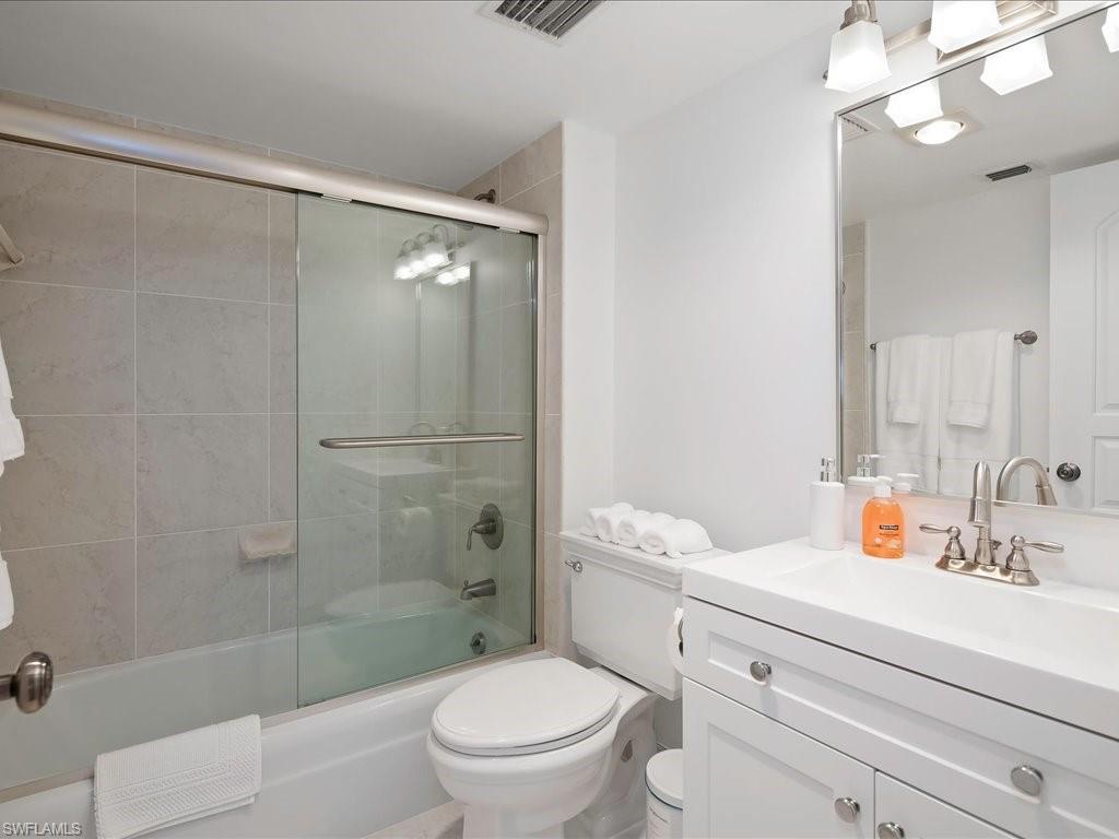 Bathroom with vanity and combined bath / shower with glass door
