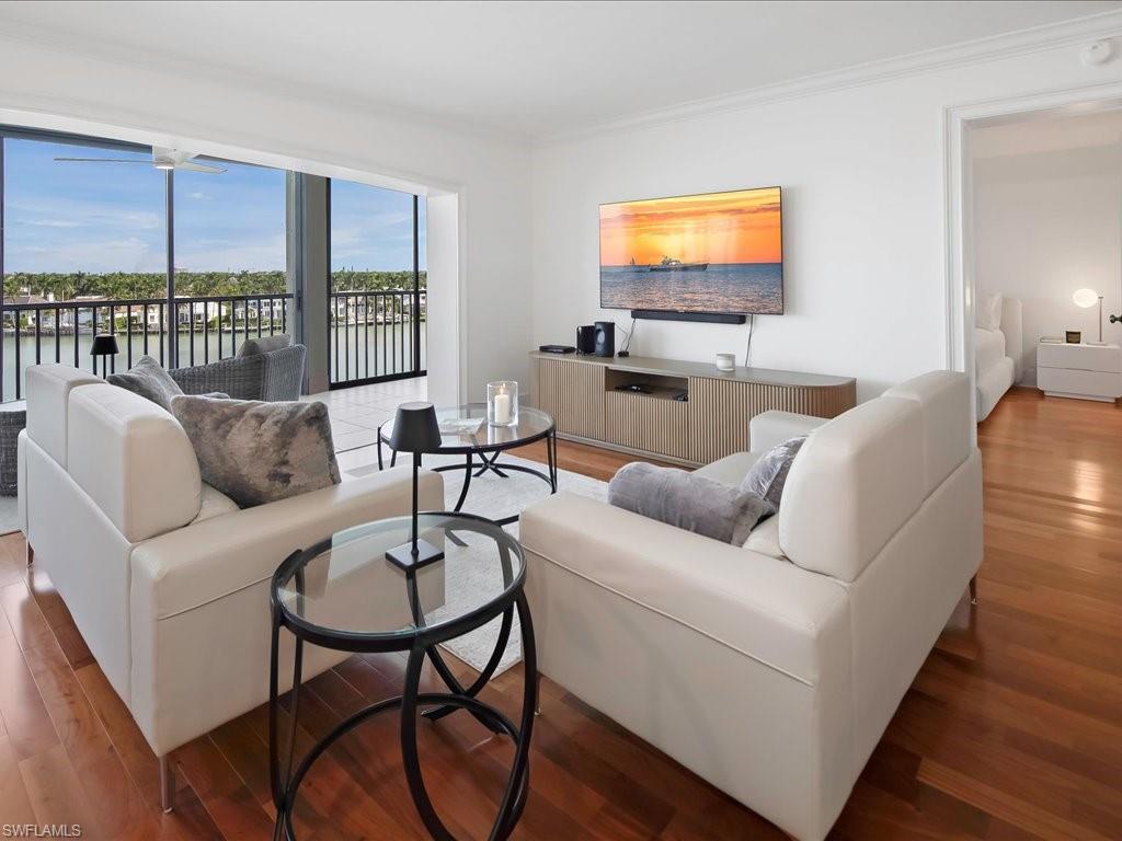 Living area with wood finished floors, ornamental molding, and a water view