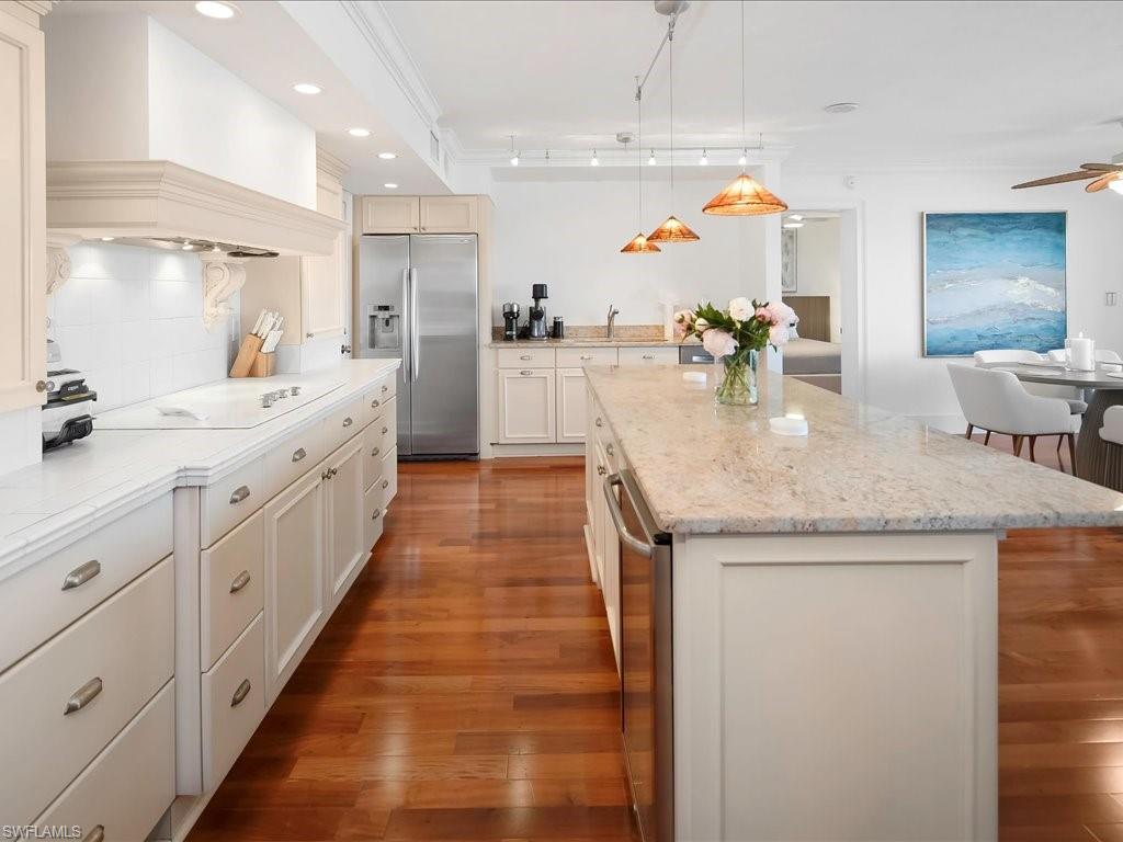 Kitchen featuring stainless steel refrigerator with ice dispenser, a ceiling fan, decorative light fixtures, decorative backsplash, and a center island