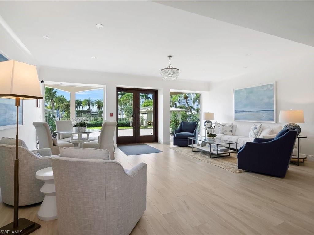 Living room with light wood-type flooring, french doors, recessed lighting, and a chandelier