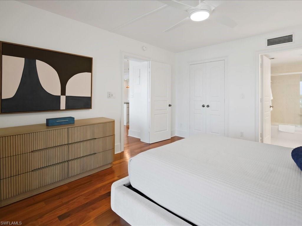 Bedroom with wood finished floors, ceiling fan, radiator heating unit, and a closet