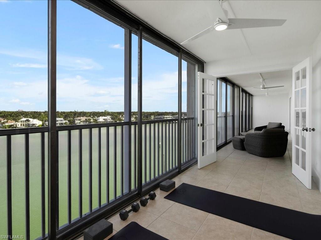 Sunroom featuring a water view, tile patterned flooring, french doors, and a wall of windows