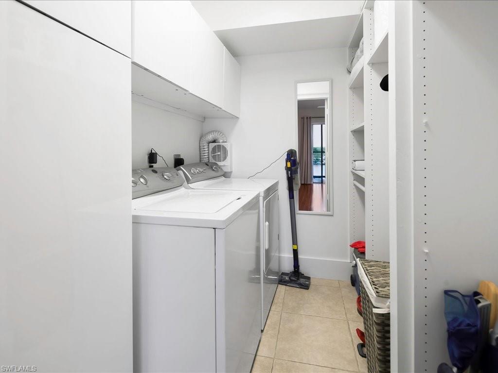 Laundry area with light tile patterned floors, independent washer and dryer, and cabinet space
