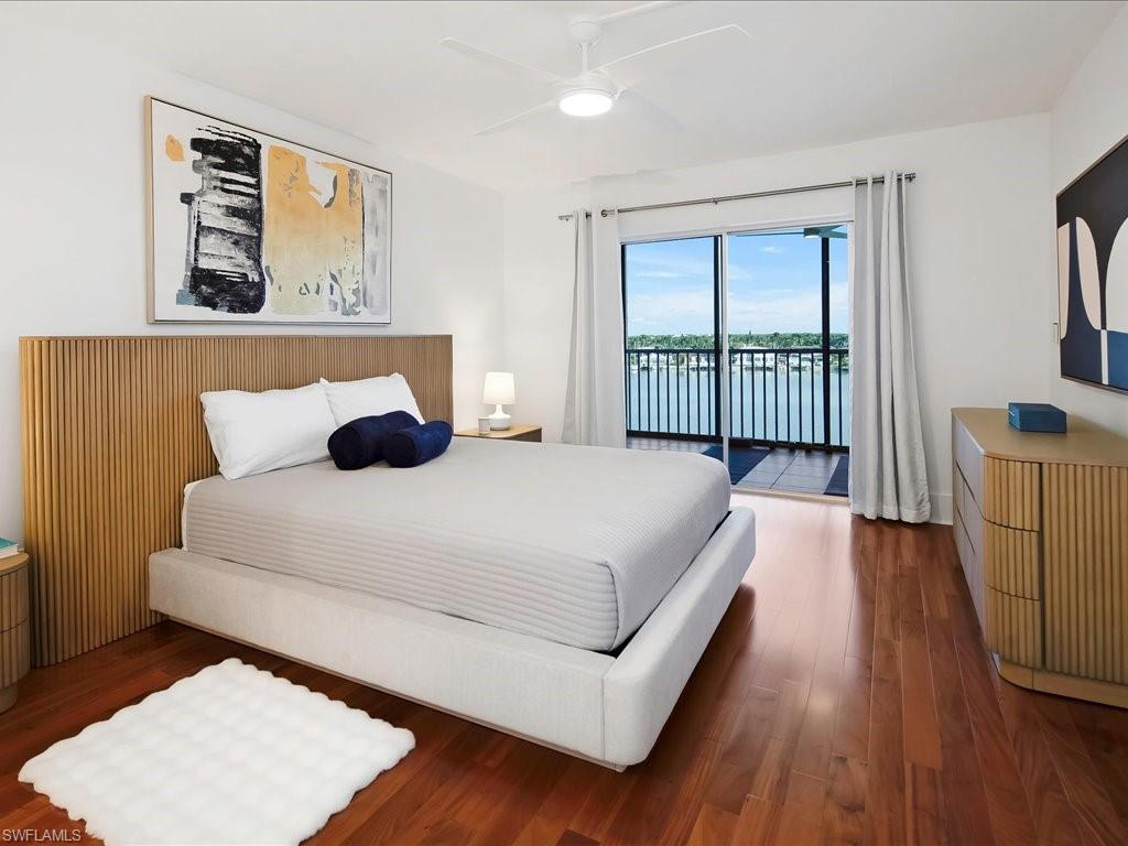Bedroom featuring access to outside, wood finished floors, a ceiling fan, and a water view