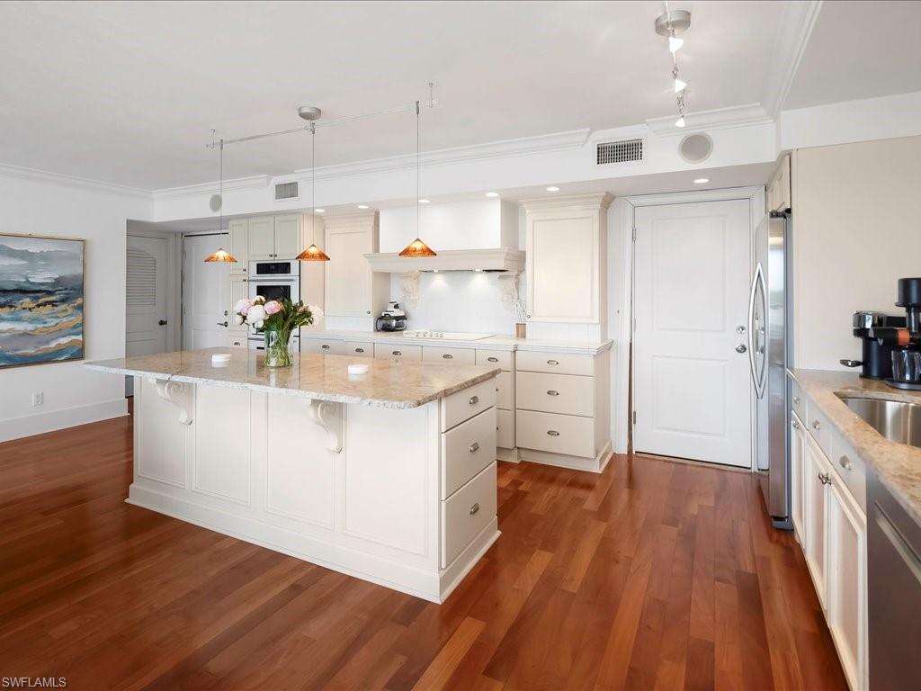 Kitchen featuring crown molding, light stone countertops, a center island, a kitchen bar, and appliances with stainless steel finishes