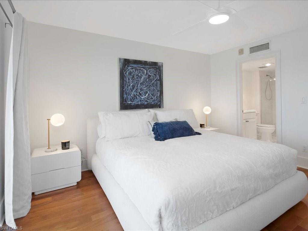 Bedroom with wood finished floors, ceiling fan, and ensuite bathroom