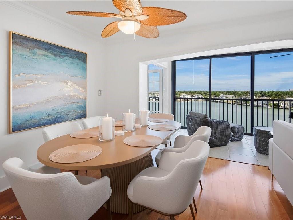 Dining space featuring healthy amount of natural light, a water view, light wood-type flooring, ceiling fan, and crown molding