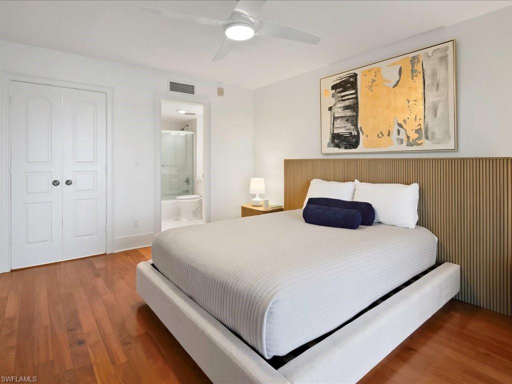 Bedroom with wood finished floors, a closet, a ceiling fan, and connected bathroom