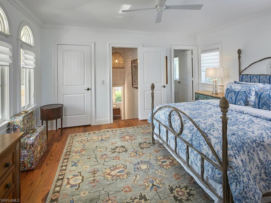 Bedroom with multiple windows, ornamental molding, wood finished floors, and a ceiling fan
