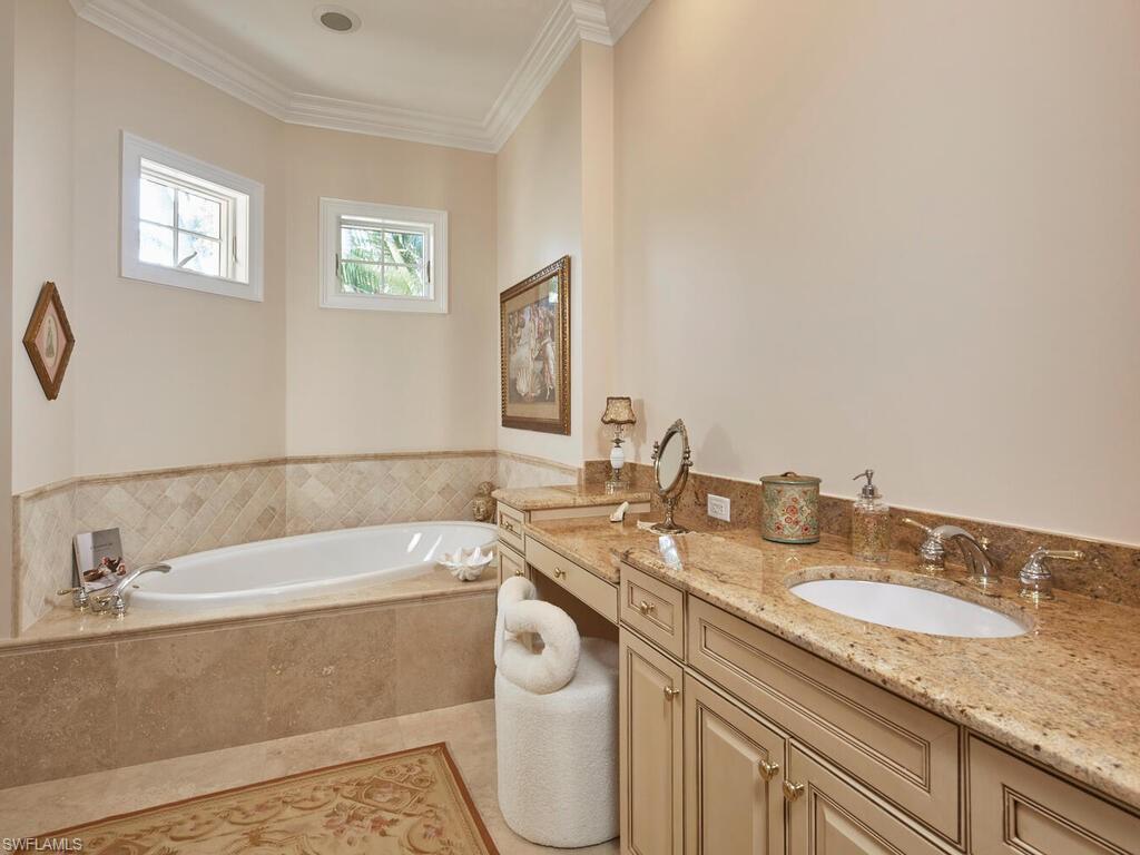Bathroom with vanity, a garden tub, ornamental molding, and light tile patterned flooring