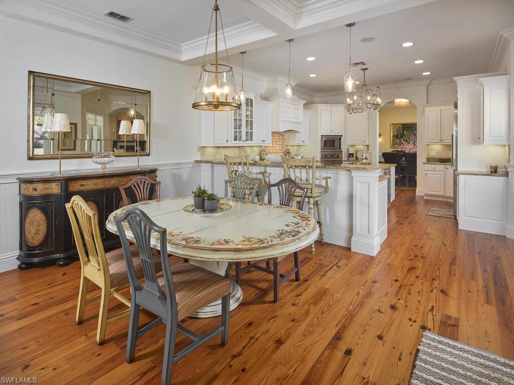 Dining room featuring ornamental molding, a chandelier, light wood finished floors, recessed lighting, and wainscoting