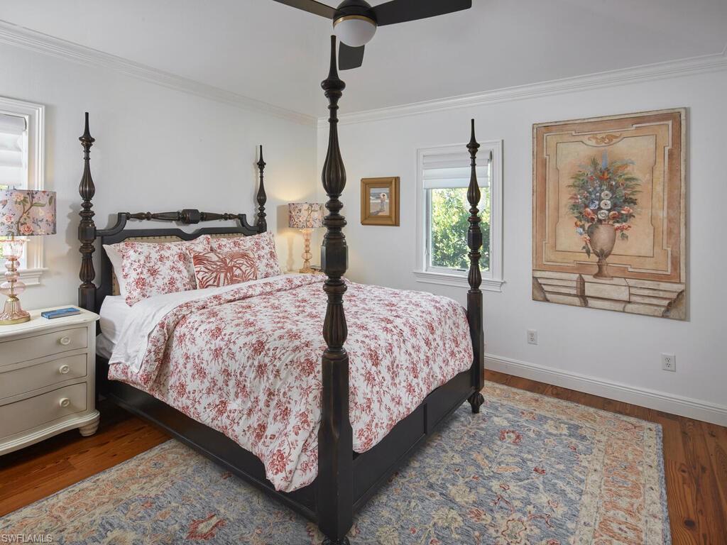 Bedroom featuring dark wood finished floors, ornamental molding, and ceiling fan