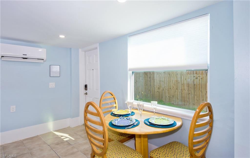 Dining area with light tile patterned flooring, an AC wall unit, and recessed lighting - Virtually Edited Image