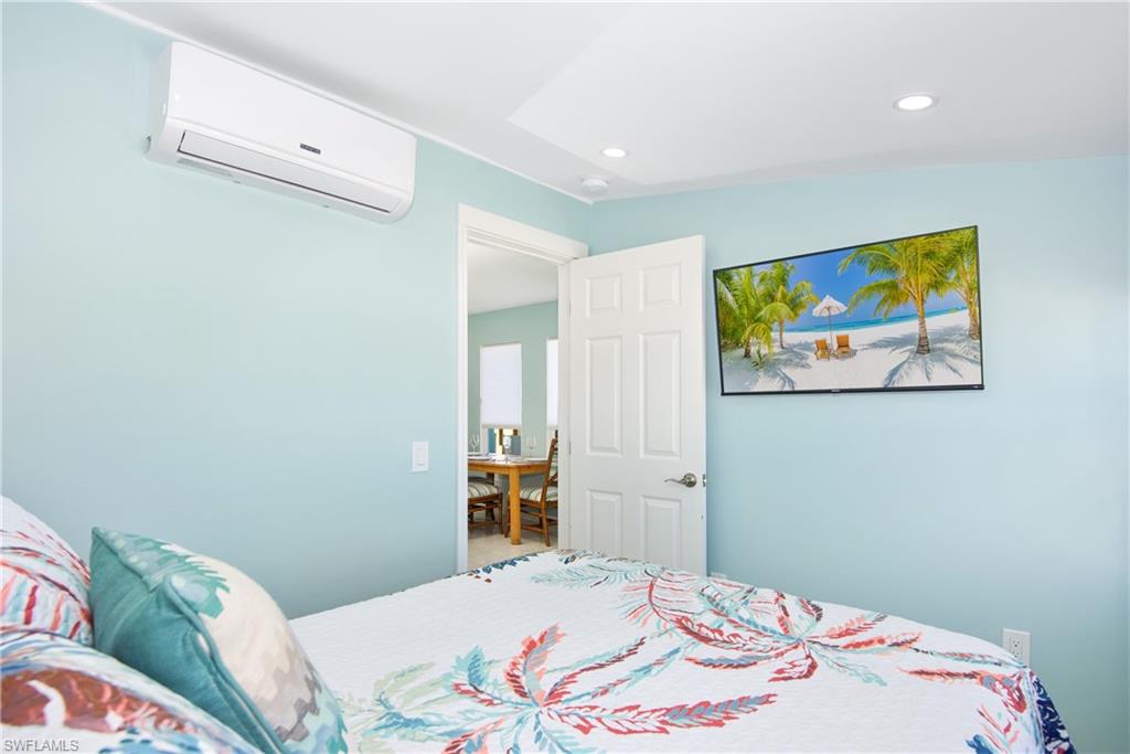 Bedroom with a wall mounted AC and recessed lighting - Virtually Edited Image