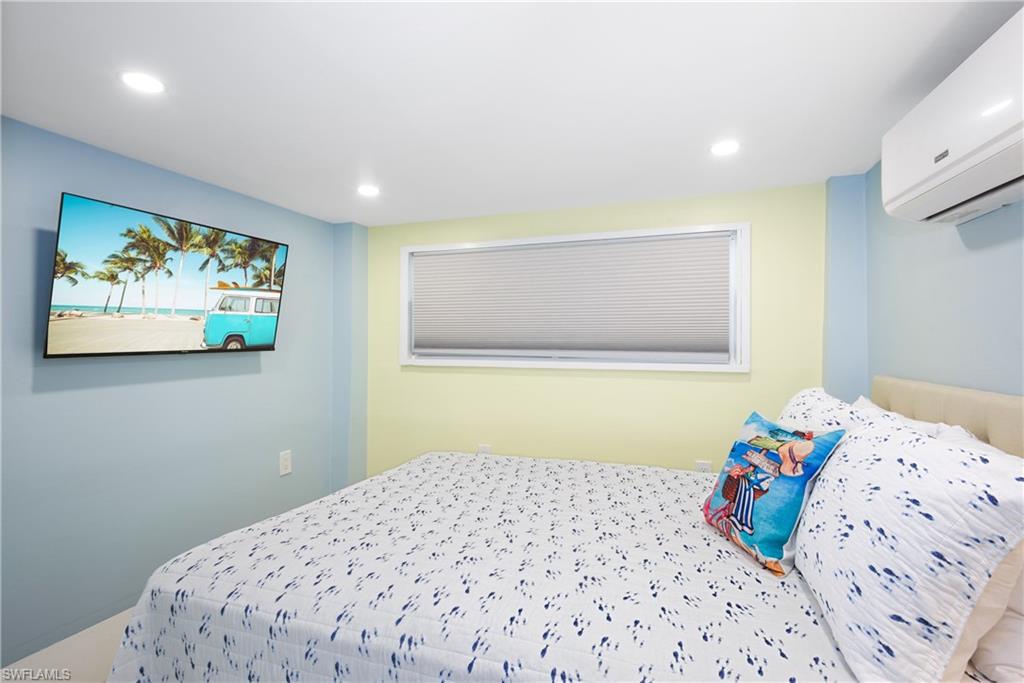 Bedroom featuring a wall unit AC and recessed lighting - Virtually Edited Image