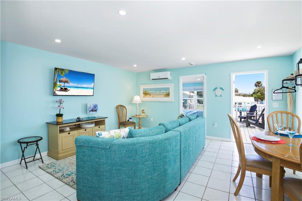 Living area with light tile patterned floors, recessed lighting, and a wall mounted air conditioner - Virtually Edited Image