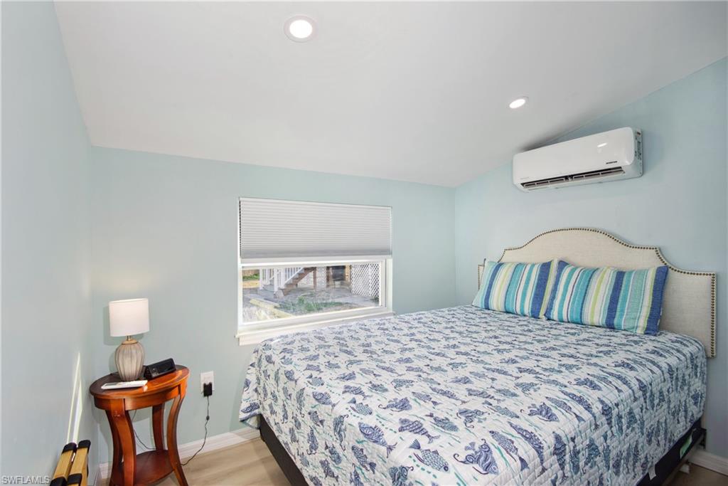 Bedroom with recessed lighting, vaulted ceiling, light wood-style flooring, and a wall mounted AC - Virtually Edited Image