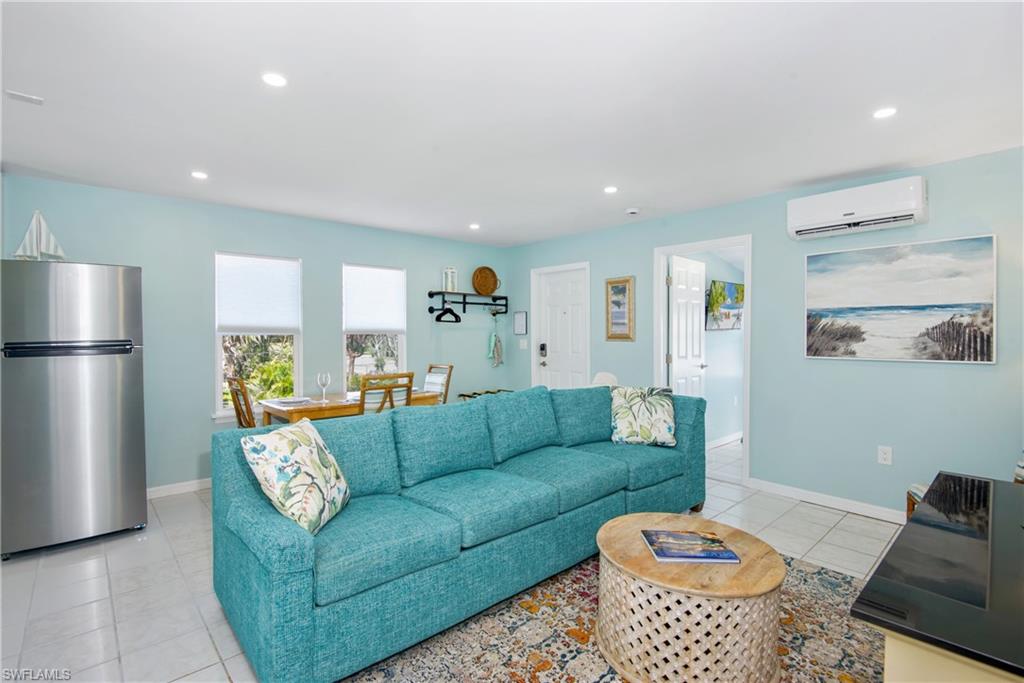 Living room featuring recessed lighting, light tile patterned flooring, and an AC wall unit - Virtually Edited Image