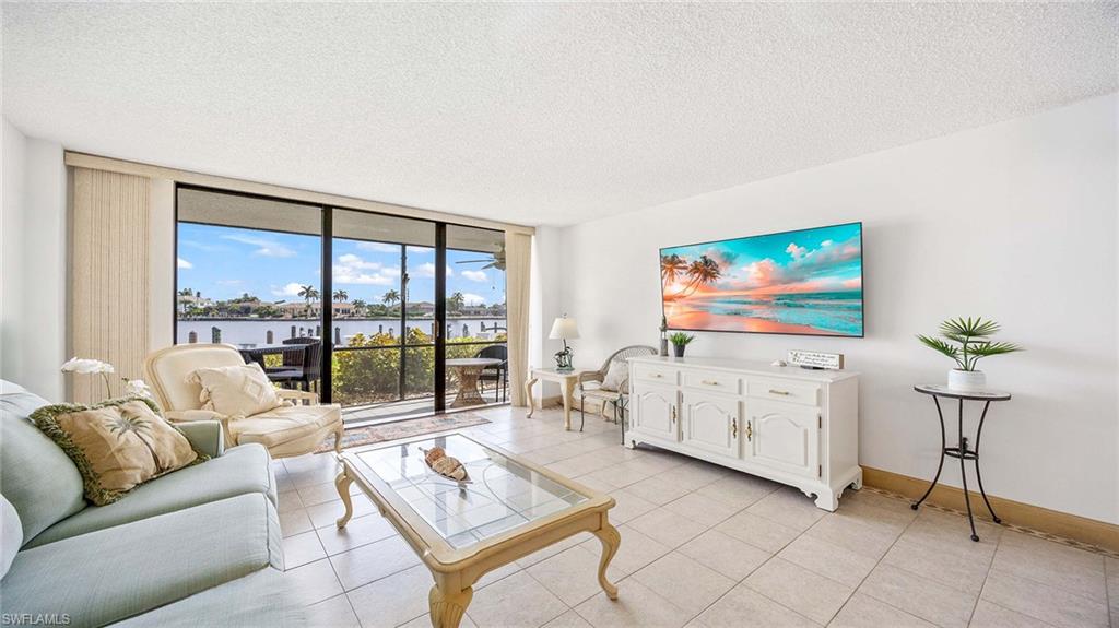 Living area with floor to ceiling windows, a textured ceiling, and light tile patterned flooring