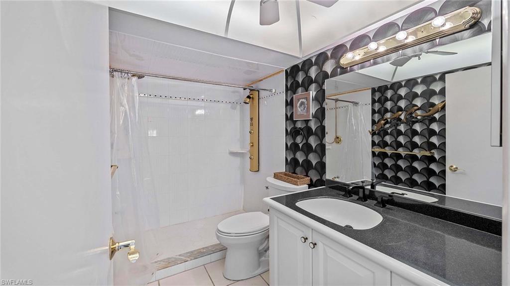 Bathroom featuring vanity, a shower stall, light tile patterned floors, and a ceiling fan