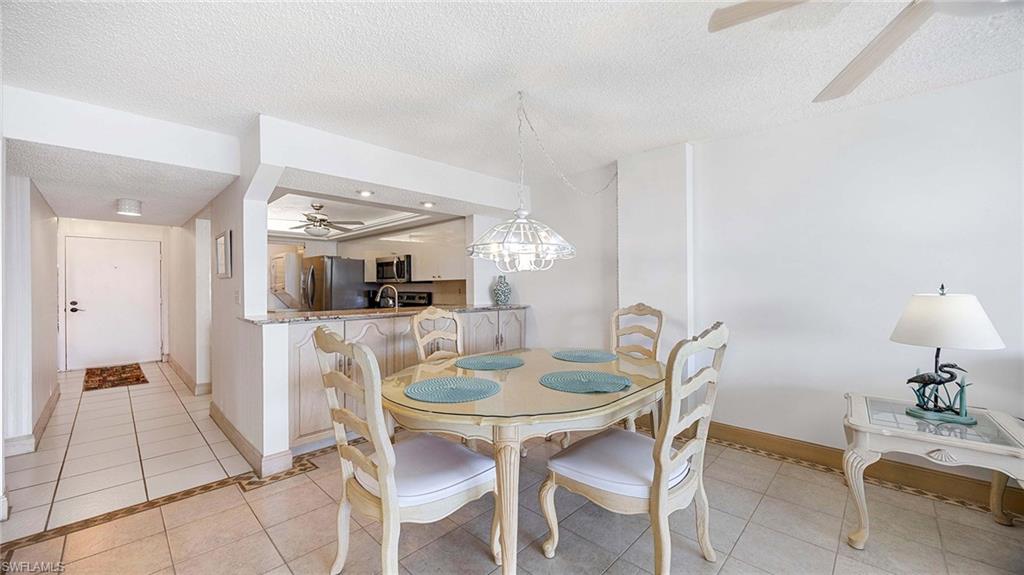 Dining space featuring ceiling fan, light tile patterned flooring, a textured ceiling, and a chandelier